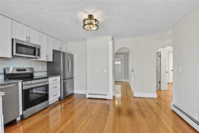 kitchen featuring a baseboard heating unit, stainless steel appliances, tasteful backsplash, and white cabinetry