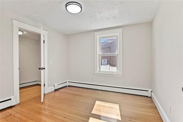 unfurnished bedroom with a baseboard heating unit, a textured ceiling, and hardwood / wood-style flooring