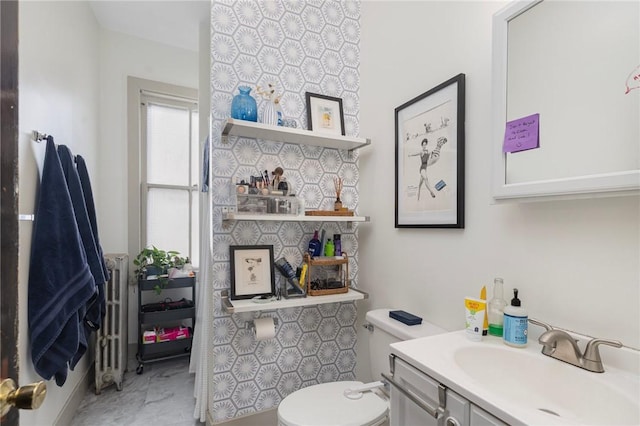 half bathroom featuring marble finish floor, toilet, vanity, and radiator heating unit