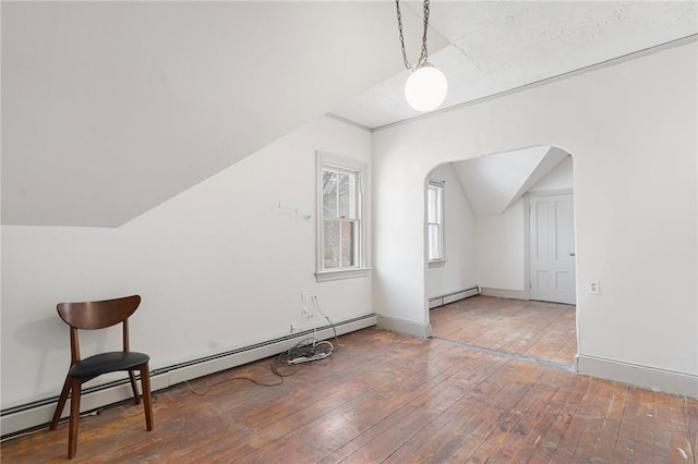 additional living space featuring lofted ceiling, a baseboard radiator, arched walkways, and hardwood / wood-style floors