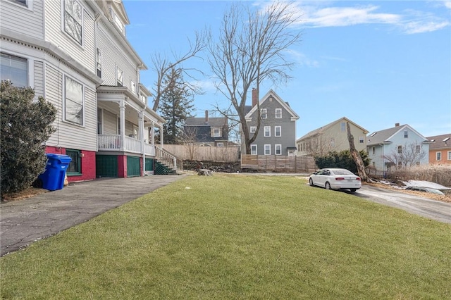 view of yard featuring a residential view, covered porch, and stairs