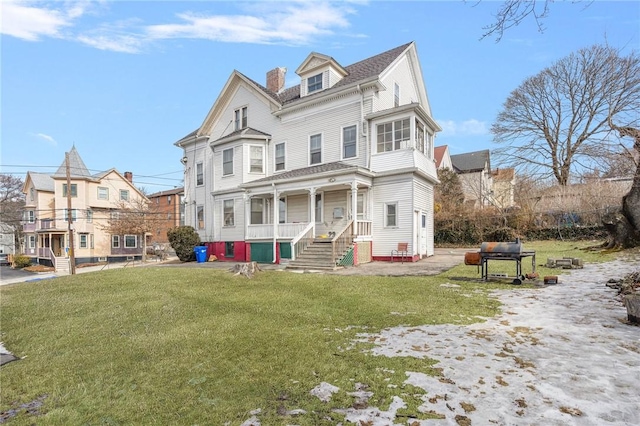 view of front of property with a chimney, a porch, and a front yard