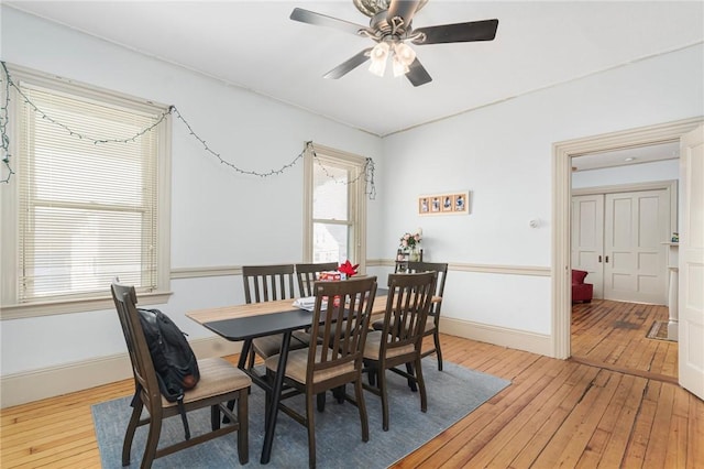 dining space featuring light wood finished floors, a ceiling fan, and baseboards