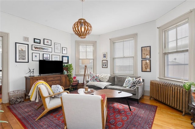 living room featuring light wood-style floors, a healthy amount of sunlight, and radiator heating unit