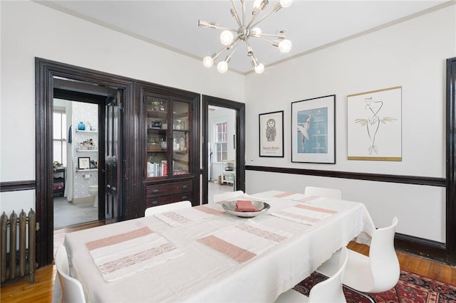 dining space featuring a notable chandelier, ornamental molding, and light wood-style floors