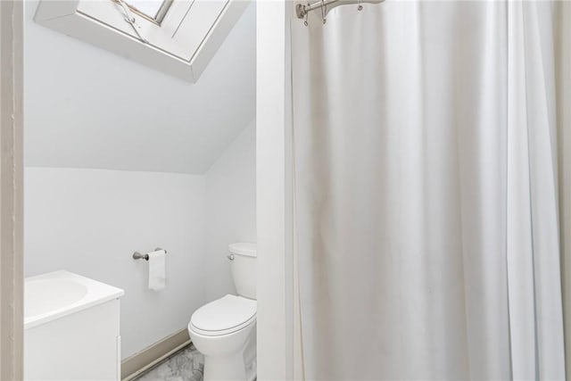 bathroom with vaulted ceiling, marble finish floor, vanity, and toilet