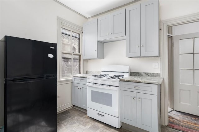 kitchen with freestanding refrigerator, a healthy amount of sunlight, light countertops, and gas range gas stove