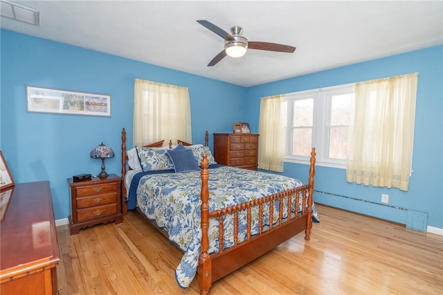 bedroom with light wood-style flooring, visible vents, baseboards, a ceiling fan, and baseboard heating