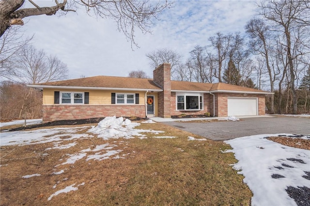 single story home featuring a garage, brick siding, driveway, and a chimney