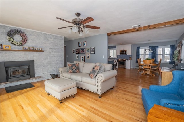 living room with light wood finished floors, visible vents, and a ceiling fan