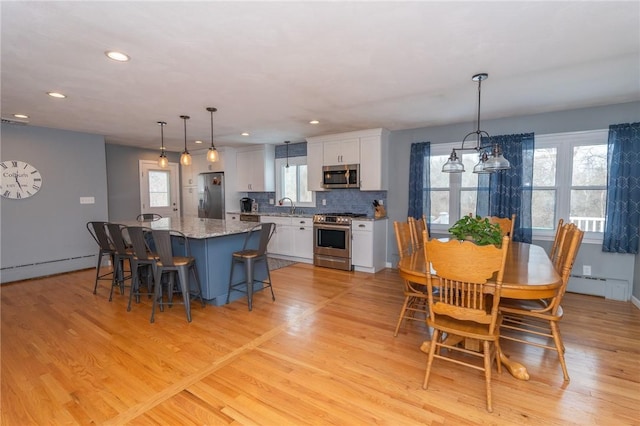 dining space with light wood finished floors, a baseboard radiator, and recessed lighting