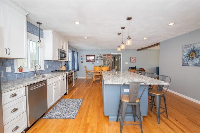 kitchen with stainless steel appliances, white cabinets, a kitchen island, and a breakfast bar area