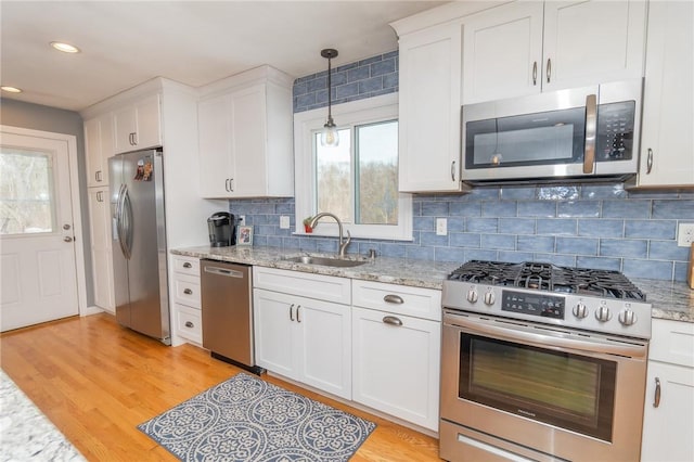 kitchen featuring light stone counters, appliances with stainless steel finishes, a sink, and white cabinetry