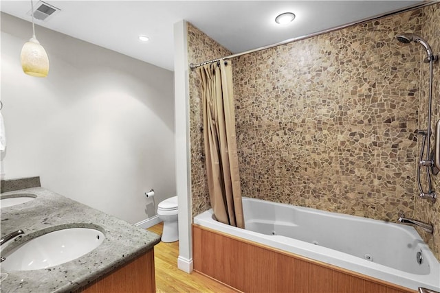 bathroom featuring visible vents, toilet, wood finished floors, a combined bath / shower with jetted tub, and a sink