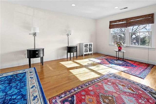 living area with recessed lighting, wood finished floors, visible vents, and baseboards