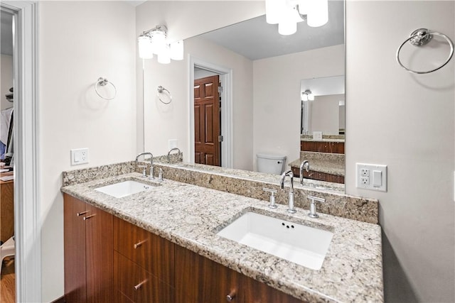 bathroom featuring toilet, double vanity, and a sink