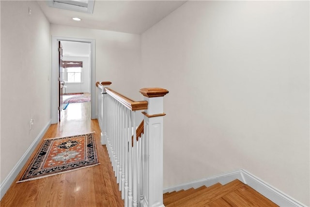 hallway with attic access, baseboards, an upstairs landing, and wood finished floors