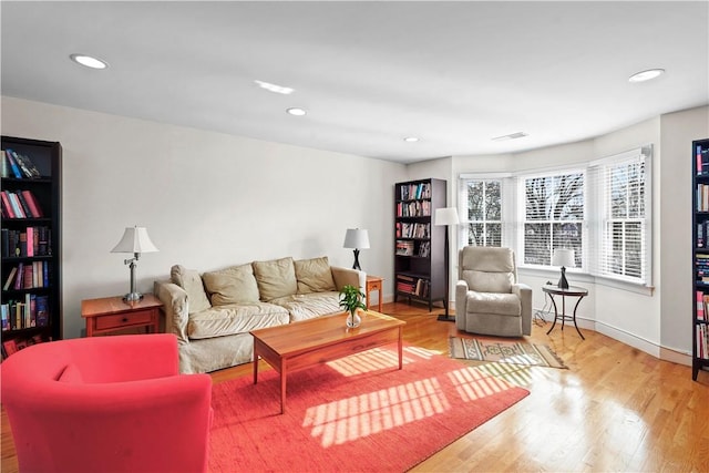 living room with recessed lighting, visible vents, baseboards, and wood finished floors