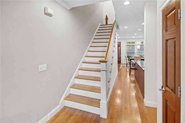 stairs with baseboards, wood finished floors, and recessed lighting