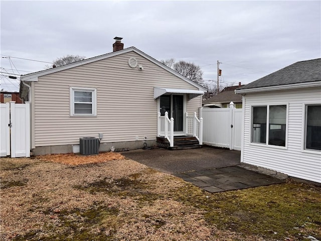 back of property with a chimney, a gate, a patio area, central AC, and fence