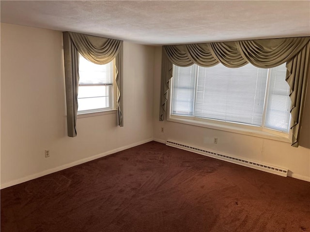 empty room with a baseboard heating unit, dark colored carpet, and baseboards