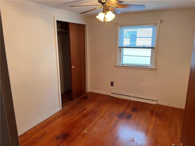 unfurnished bedroom with baseboard heating, hardwood / wood-style flooring, and baseboards