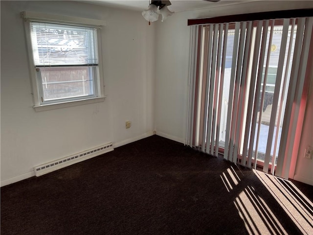 spare room with baseboards, dark carpet, and baseboard heating