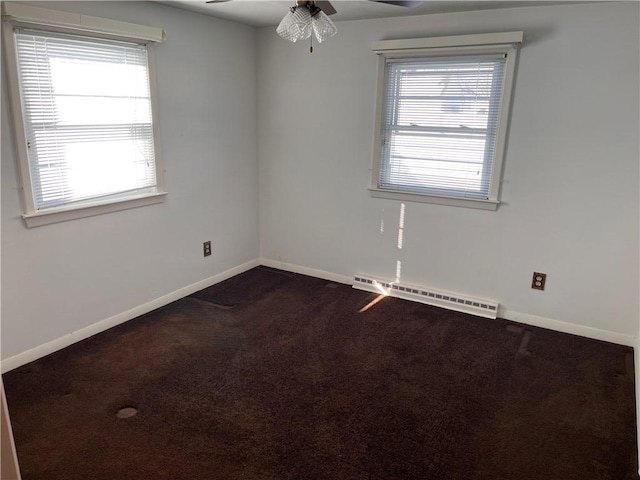 unfurnished room featuring a wealth of natural light, dark colored carpet, baseboards, and baseboard heating