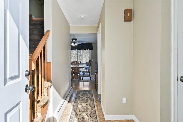 hall with a baseboard heating unit, stairway, and baseboards