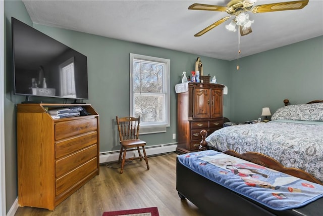 bedroom with ceiling fan, baseboard heating, wood finished floors, and baseboards