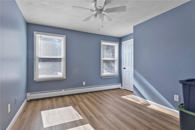 empty room with a baseboard radiator, baseboards, ceiling fan, and wood finished floors