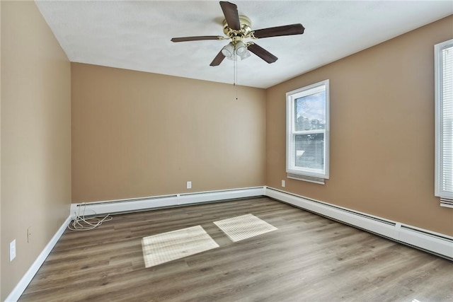 empty room with a baseboard heating unit, ceiling fan, wood finished floors, and baseboards