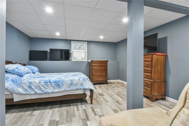 bedroom with a drop ceiling, wood finished floors, and baseboards