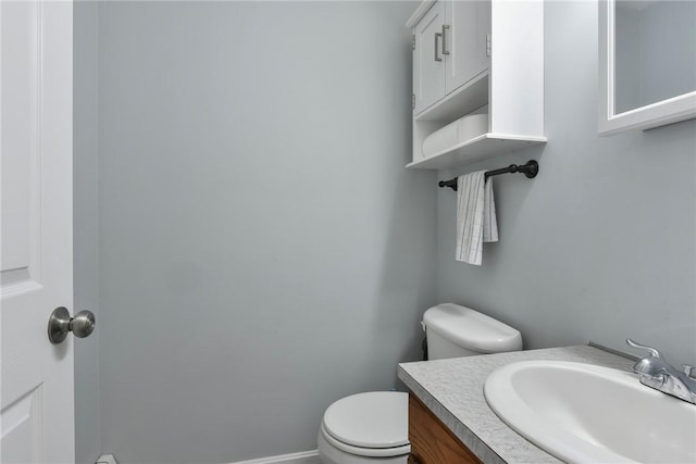 bathroom with baseboards, vanity, and toilet