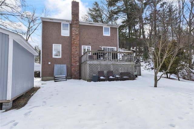 snow covered property featuring a chimney and a deck