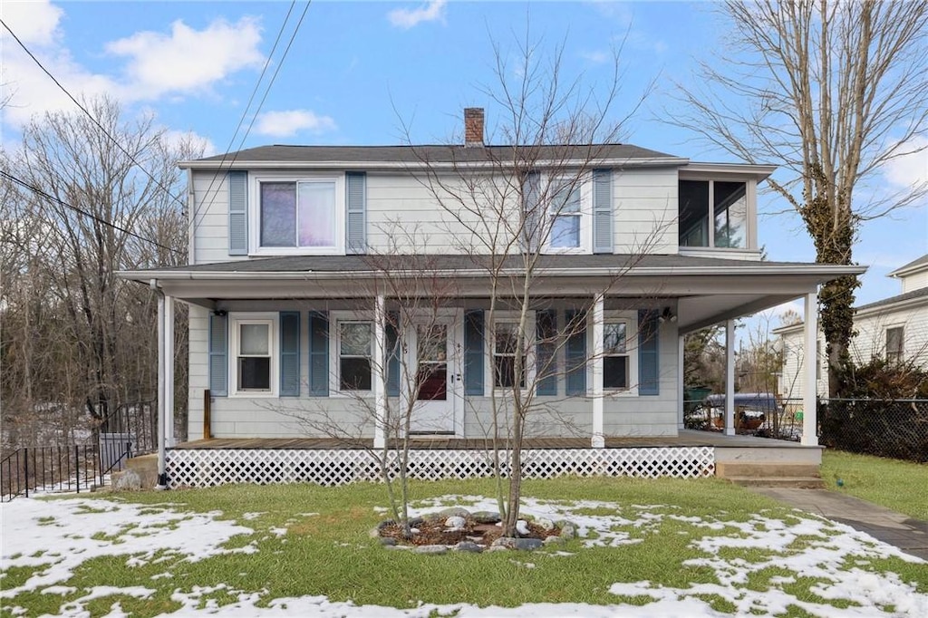 view of front of house featuring covered porch, a chimney, a front yard, and fence