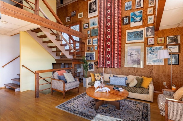 sitting room with stairs, a high ceiling, wood finished floors, and wooden walls