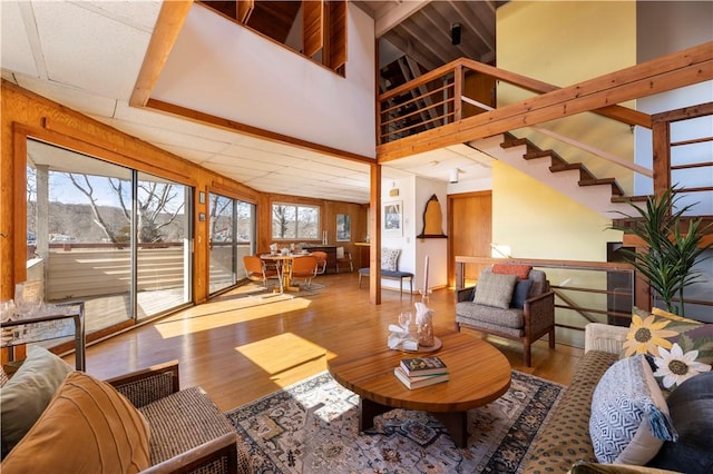 living area with a drop ceiling, wood finished floors, a towering ceiling, and wooden walls