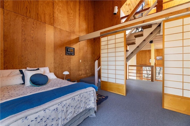 bedroom featuring wood walls, carpet, and a towering ceiling