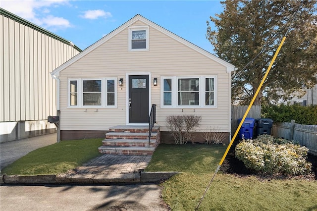 bungalow-style house with entry steps, a front yard, and fence