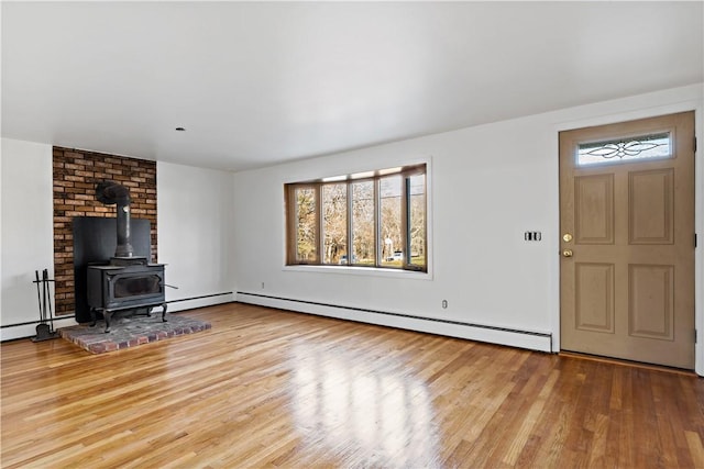 unfurnished living room with a wood stove, baseboard heating, and wood finished floors