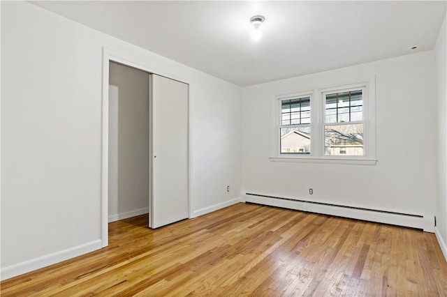 unfurnished bedroom featuring light wood-type flooring, a closet, baseboards, and baseboard heating