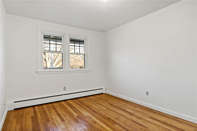 empty room featuring baseboard heating, wood finished floors, and baseboards