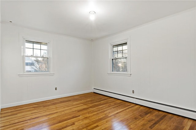 empty room featuring baseboards, crown molding, light wood finished floors, and baseboard heating