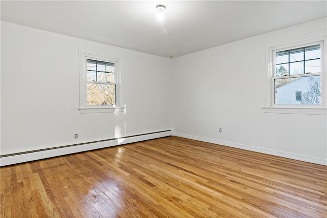 unfurnished room featuring baseboards, light wood-style flooring, and baseboard heating