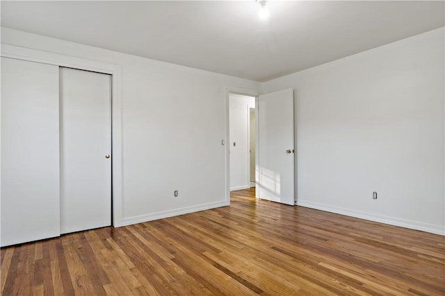 unfurnished bedroom with a closet, wood finished floors, and baseboards