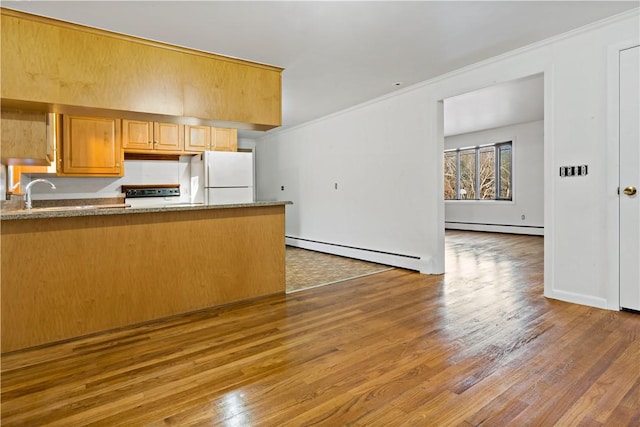 kitchen with a baseboard heating unit, freestanding refrigerator, and wood finished floors