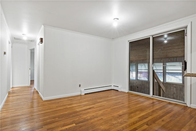 spare room with a baseboard radiator, crown molding, baseboards, and wood finished floors