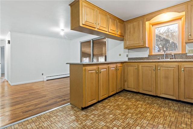 kitchen featuring a peninsula, stone counters, a baseboard radiator, and crown molding