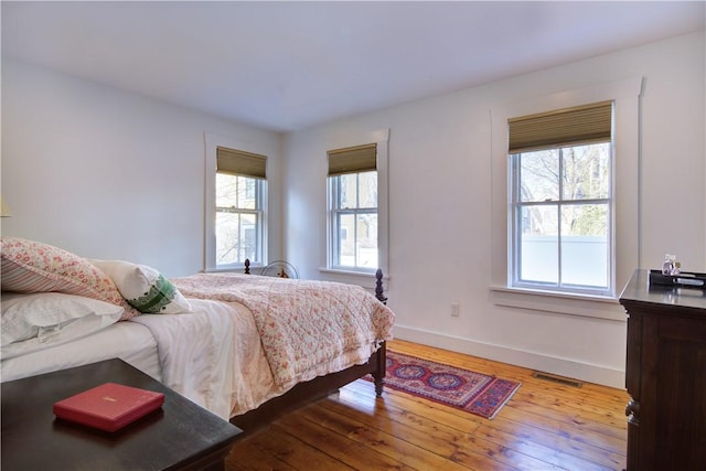 bedroom with multiple windows, baseboards, and wood-type flooring